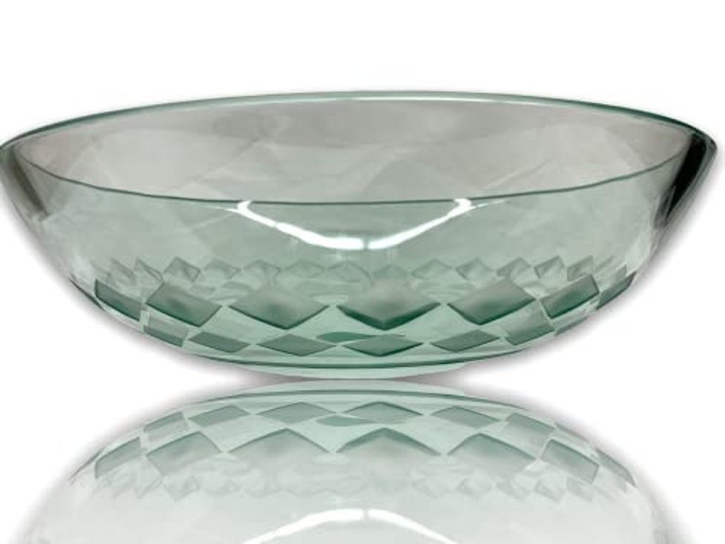 May include: A large, clear glass bowl with a geometric pattern etched into the bottom. The bowl is oval shaped and has a slight green tint.