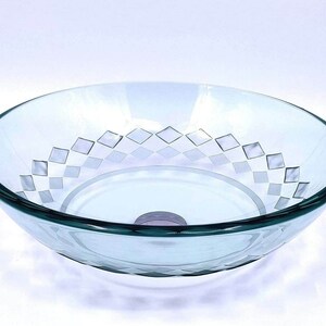 May include: A clear glass bathroom sink with a diamond pattern etched into the bottom. The sink is round and has a smooth, polished finish.