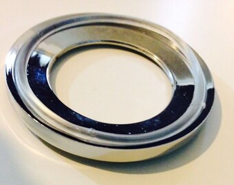 May include: A shiny, silver-toned metal ring with a smooth, rounded edge. The ring has a large, circular opening in the center.