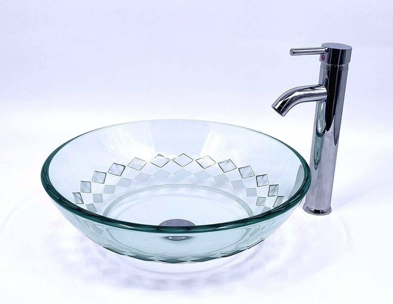May include: A clear glass vessel sink with a diamond pattern etched into the bottom. The sink is paired with a chrome faucet.