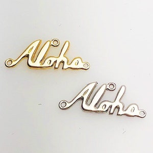 May include: Two metal charms with the word "Aloha" written in a cursive font. The charm on the top is gold and the charm on the bottom is silver.