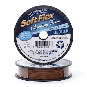 Op de afbeelding: Een spoel bruin Soft Flex kralendraad in de kleur Butterscotch Imperial Topaz. De spoel is gemarkeerd met "Medium" en heeft een treksterkte van 26 lbs. De draad is 9 meter lang en heeft een diameter van 0,48 mm. Het is gemaakt in de VS.