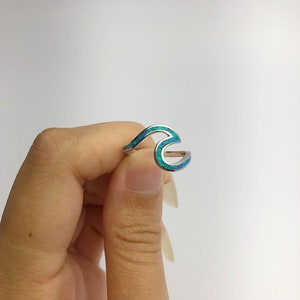 May include: A silver ring with a blue and green opal wave design.