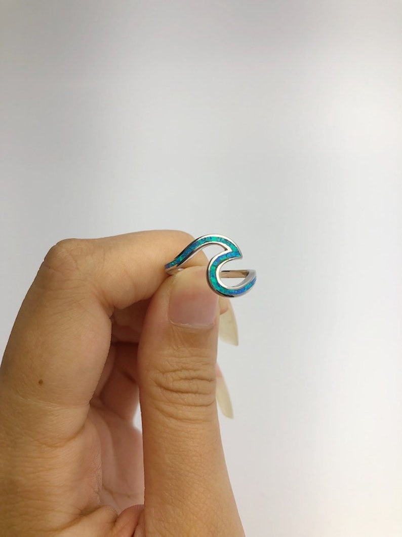 May include: A silver ring with a blue and green opal wave design.