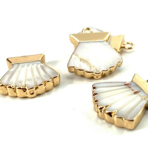 Könnte beinhalten: Drei goldfarbene Muschel-Anhänger aus Metall mit weißen Perlmutteinlagen. Die Anhänger haben eine Öse zum Anbringen an Schmuck oder andere Bastelarbeiten.
