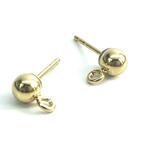 May include: Two gold-toned earring posts with a small ball at the top and a jump ring attached to the ball.