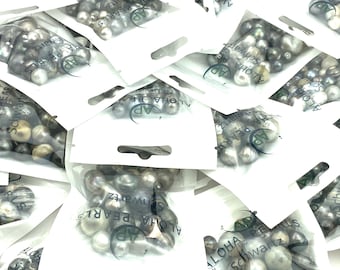 May include: Multiple small white bags filled with black and white pearls. The bags have a label that reads "Aloha Pearls Schwartz".