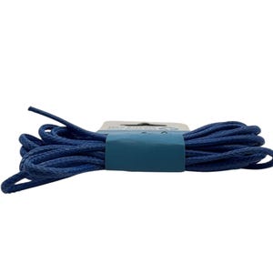 Puede incluir: Un paquete de cordones azul marino, enrollados y asegurados con una banda de papel azul. Los cordones están hechos de un material redondo y trenzado. El fondo es blanco.