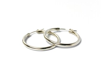 May include: A pair of silver hoop earrings. The hoops are thick and have a smooth, polished finish.