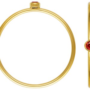 May include: A simple gold band ring with a small red gemstone set in the center.