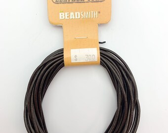 Op de afbeelding: Een rol bruin lederen koord, 300 cm lang, verpakt op een kaart met de tekst "Leather Cord" en "The Beadsmith".