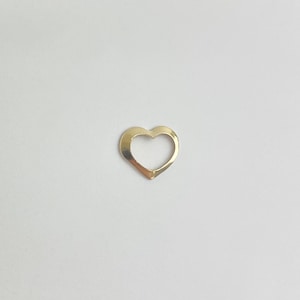 May include: A gold-colored heart-shaped charm with a hollow center.