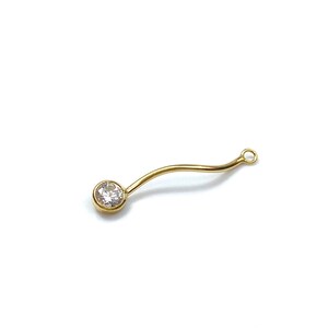 Può includere: Connettore per gioielli dorato con un cristallo rotondo trasparente a un'estremità e un anello all'altra.