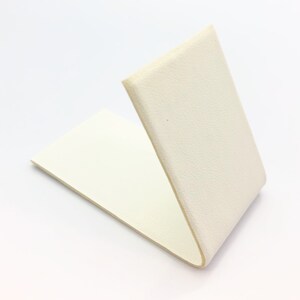 May include: A white, rectangular piece of foam with a folded edge, creating a V-shape.