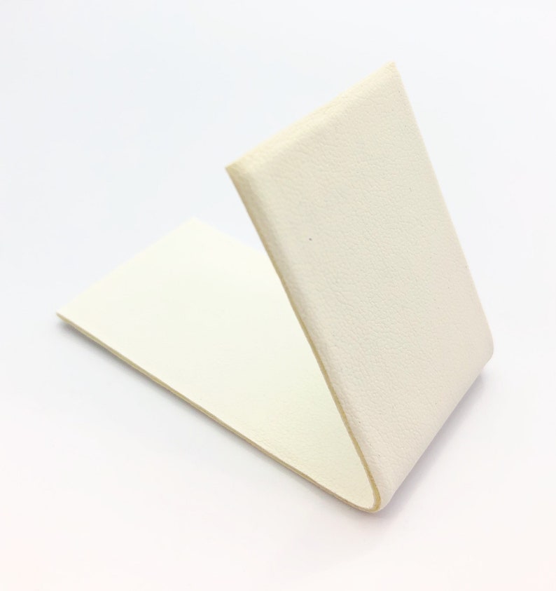 May include: A white, rectangular piece of foam with a folded edge, creating a V-shape.