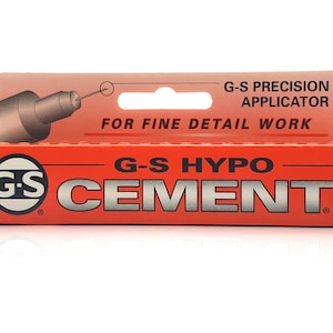 May include: A red and white box with a black circle containing the letters "G-S" and the words "G-S HYPO CEMENT" in black. The box has a hang hole and a small image of a precision applicator with a needle.