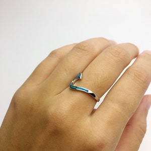 May include: A silver ring with a blue opal inlay in the shape of a curved line.