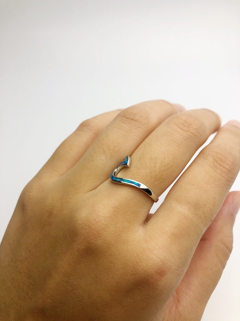 May include: A silver ring with a blue opal inlay in the shape of a curved line.