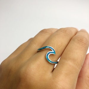 May include: A silver ring with a blue opal wave design.