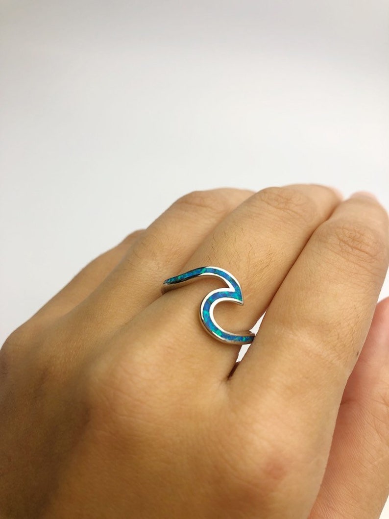 May include: A silver ring with a blue opal wave design.