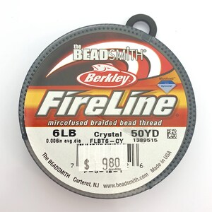 May include: A spool of 6lb Berkley FireLine Crystal microfused braided bead thread in a gray container with a black lid. The spool is labeled with the brand name, product name, weight, color, and yardage. The label also includes a barcode and the price of $9.80.