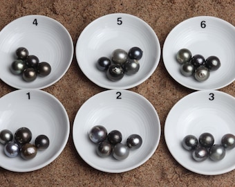 May include: Six white ceramic dishes with black numbers 1 through 6 on them. Each dish contains a group of black pearls.