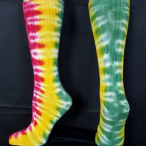 May include: A pair of tie-dye socks with a red, yellow, and green color scheme. The socks are made of cotton and have a ribbed texture.