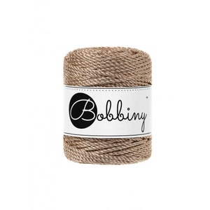 May include: A spool of brown and gold rope yarn with the word "Bobbiny" printed on the label.