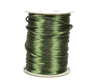 May include: A spool of dark green waxed cotton cord. The cord is wound tightly around the spool, which is made of white cardboard.
