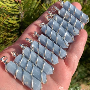 May include: A collection of ten blue celestite crystal pendants wrapped in silver wire. The pendants are all different sizes and shapes, but they are all beautiful and unique.