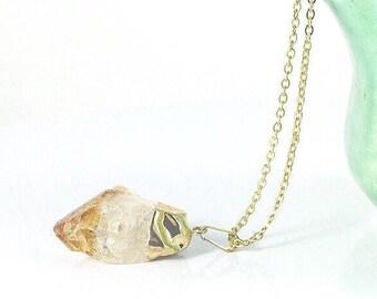 May include: A gold chain necklace with a raw, clear and orange crystal pendant.
