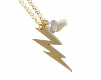May include: A gold chain necklace with a lightning bolt pendant and a clear gemstone charm.