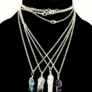 May include: Four silver chain necklaces with wire-wrapped crystal pendants. The crystals are blue, clear, pink, and purple.