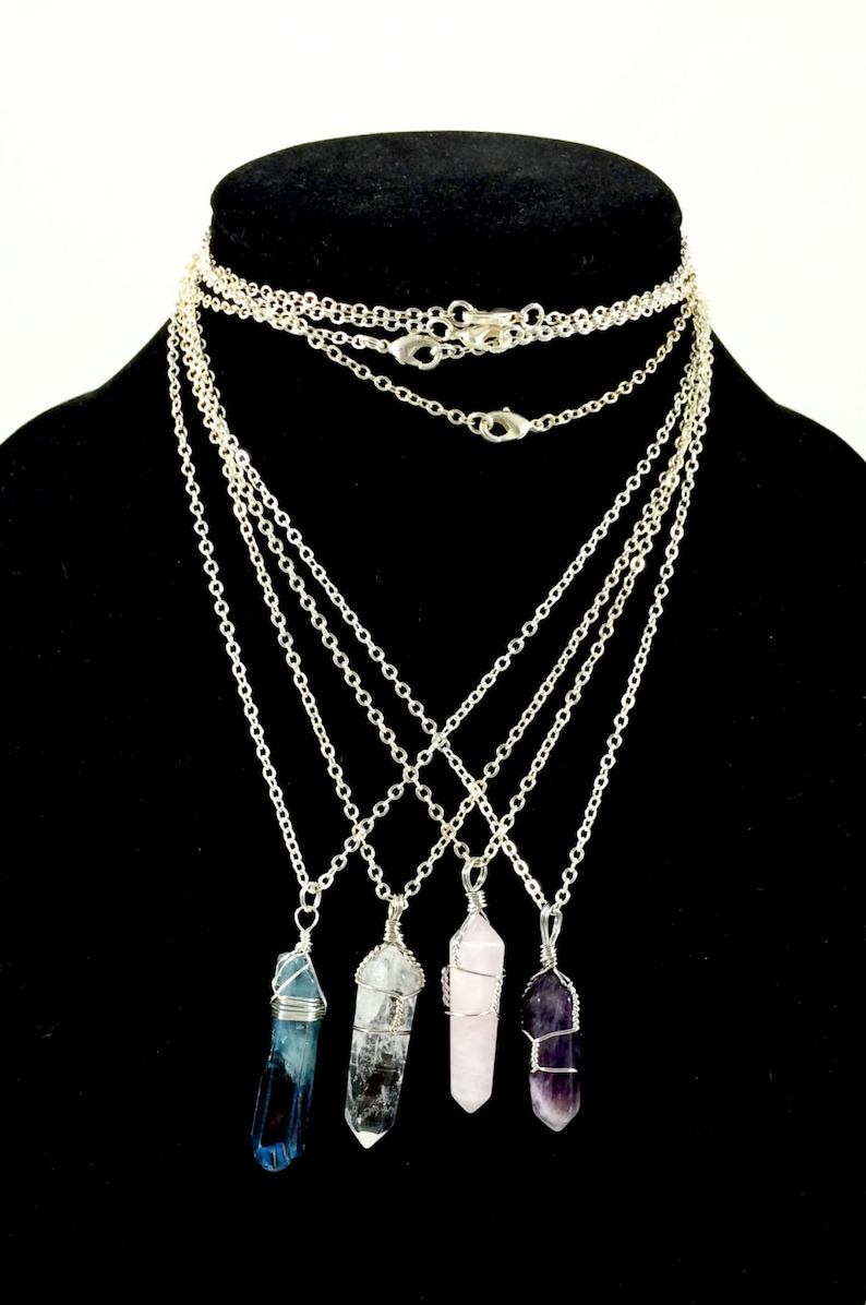 May include: Four silver chain necklaces with wire-wrapped crystal pendants. The crystals are blue, clear, pink, and purple.