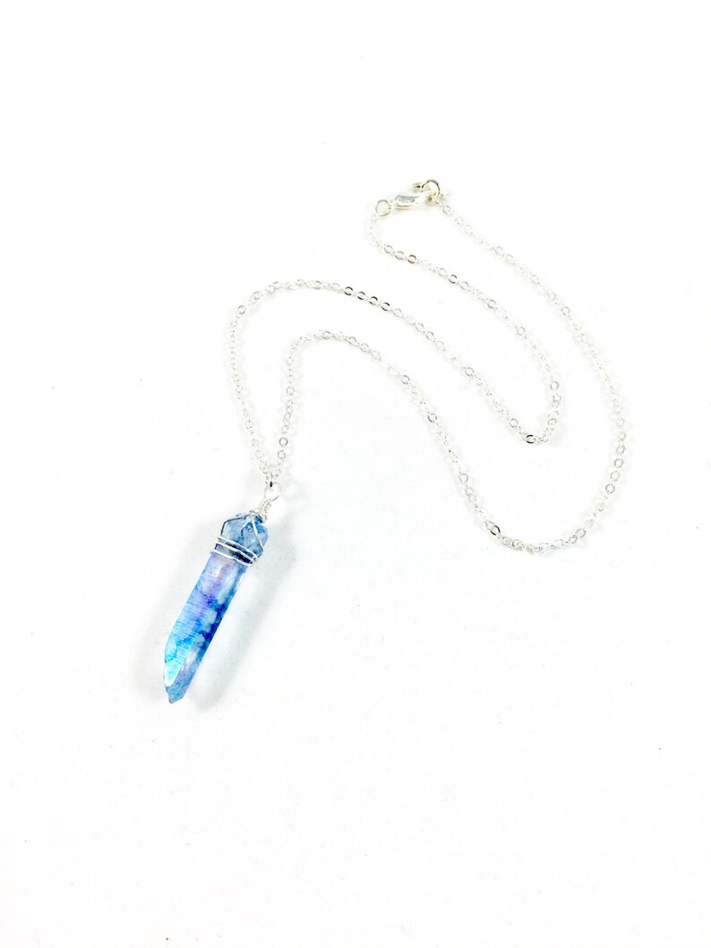 May include: A silver chain necklace with a blue crystal pendant. The crystal is wrapped in silver wire.