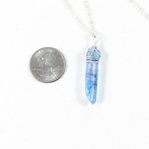 May include: A silver chain necklace with a blue crystal pendant. The crystal is wrapped in silver wire and is about the size of a US quarter.