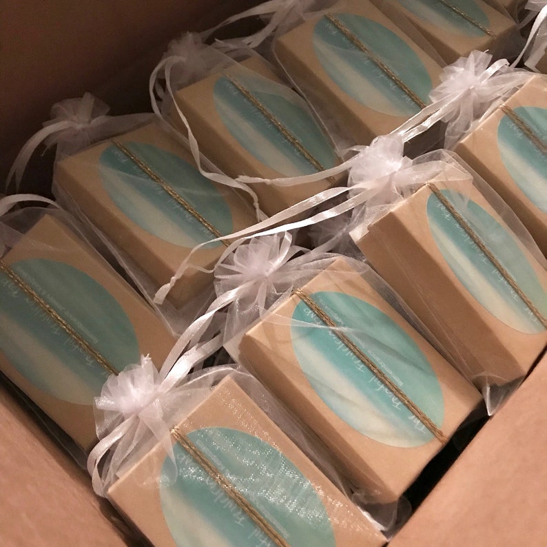 May include: A box of small, brown gift boxes with a blue and white design. Each box is wrapped in a white, sheer bag with a white ribbon.
