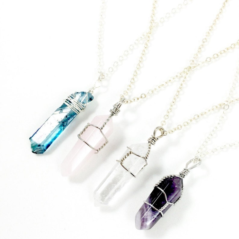 May include: Four silver chain necklaces with wire-wrapped crystal pendants. The crystals are blue, pink, clear, and purple.