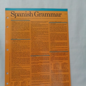 May include: An open Spanish Grammar study sheet with the title "Spanish Grammar" in large blue letters. The sheet is orange with black text and blue trim. It has three holes for binder storage.