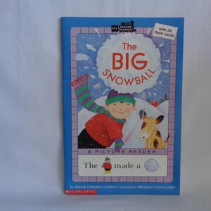 May include: A children's book titled The Big Snowball, featuring an illustration of a person in a red coat and striped scarf with a dog in a snowy landscape. The cover includes the text All Aboard Reading, with 24 flash cards, and Scholastic.