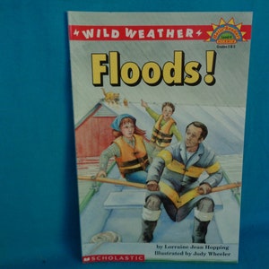 May include: A children's book cover with an illustration of three people in a boat on a flooded street. The book title is "Floods!" and is part of the "Wild Weather" series. The book is part of the Hello Reader! Science series for grades 2-3.