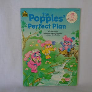 May include: A children's book cover featuring the Popples, a group of colorful, furry creatures with big eyes and fluffy tails. The book is titled "The Popples' Perfect Plan" and is illustrated with the Popples in a forest setting.