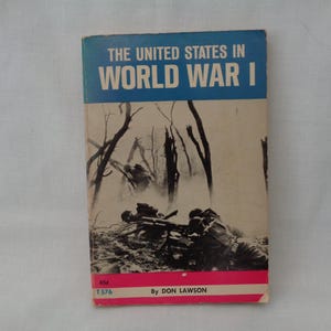 May include: A vintage book titled "The United States in World War I." The cover features a blue banner with white text, a black and white illustration of soldiers in a war scene, and a red and white stripe at the bottom. By Don Lawson.