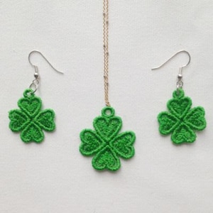 May include: A set of green four-leaf clover earrings and a necklace. The jewelry is made of green fabric and has a delicate, intricate design.