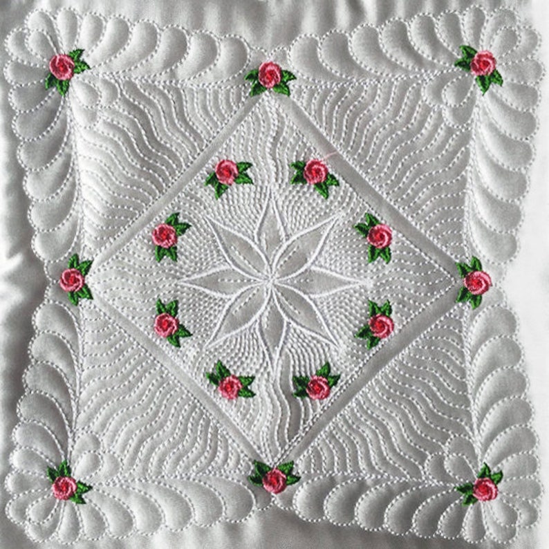 May include: White quilted fabric with a diamond pattern and a central starburst design. The fabric is decorated with small pink roses with green leaves.