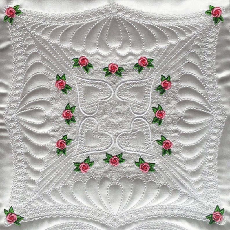 May include: White quilted fabric with a delicate pattern of hearts and swirls. The fabric is decorated with pink roses with green leaves.