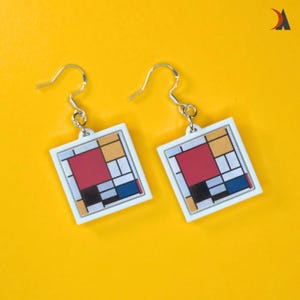 May include: Two square earrings with a Mondrian-inspired design. Each earring has a white border framing a colourful geometric pattern of red, yellow, blue, and black shapes. They hang from silver-coloured hooks against a bright yellow background.