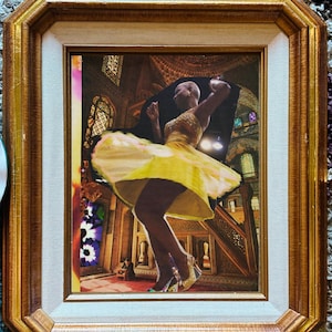 Può includere: Un'opera d'arte incorniciata con un collage di una persona che balla con un vestito giallo. La cornice è dorata con un bordo interno bianco. Lo sfondo del collage è un interno di chiesa. Un candelabro dorato è a destra.