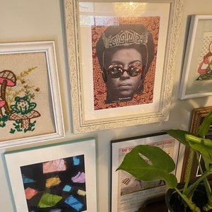 Może przedstawiać: Galeria ścienna z obrazami w ramach, w tym vintage plakat kobiety w koronie i okularach przeciwsłonecznych, haftowany obraz w ramie z grzybami i żabą, abstrakcyjny wydruk w ramie z kolorowymi kształtami oraz okładka czasopisma w ramie z zielonym liściem.