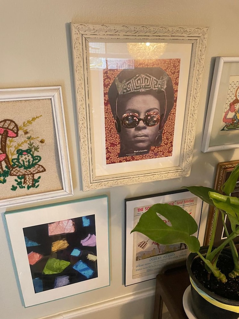 Może przedstawiać: Galeria ścienna z obrazami w ramach, w tym vintage plakat kobiety w koronie i okularach przeciwsłonecznych, haftowany obraz w ramie z grzybami i żabą, abstrakcyjny wydruk w ramie z kolorowymi kształtami oraz okładka czasopisma w ramie z zielonym liściem.